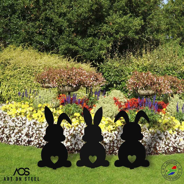 Set of 3 bunny garden ornaments with heart cut-out design — black steel silhouettes by Art on Steel, decorative metal rabbit figures for flower beds, Easter lawn décor, durable handmade outdoor decorations made in South Africa.