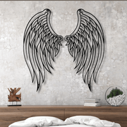 Metal angel wings wall decor on a textured wall above a wooden surface.