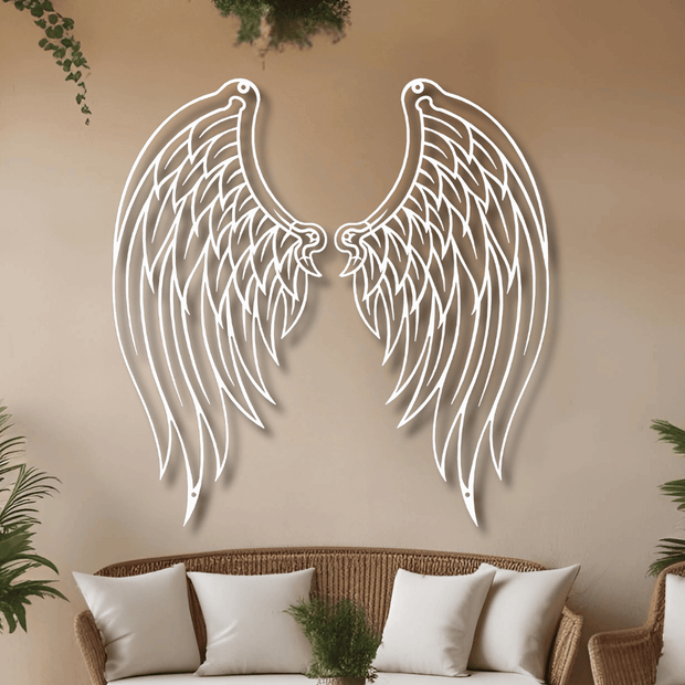 Decorative metal angel wings on a beige wall above a wicker sofa with white cushions.