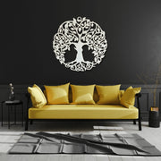 Yellow sofa with decorative pillows against a black wall with a tree of life design.