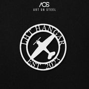 A white circular metal sign featuring a single-propeller airplane in the center. The sign is framed with the text "LHT HANGAR" at the top and "EST 2023" at the bottom. The art is shown against a dark, black background, and the "Art on Steel" logo is visible at the top.