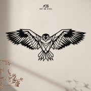 A detailed, geometric eagle metal wall art piece with its wings spread wide, shown against a simple, light-colored wall. The black steel contrasts sharply with the background, and a plant in the foreground casts a soft shadow. The "Art on Steel" logo is visible at the top