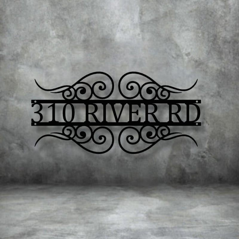 A close-up of a custom, house number sign, with the numbers 310 and the street name RIVER RD framed by decorative scrollwork. The black sign is mounted on a gray, distressed concrete wall. Art on Steel