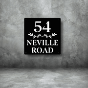 Black square sign with white text '54 Neville Road' on a gray concrete background