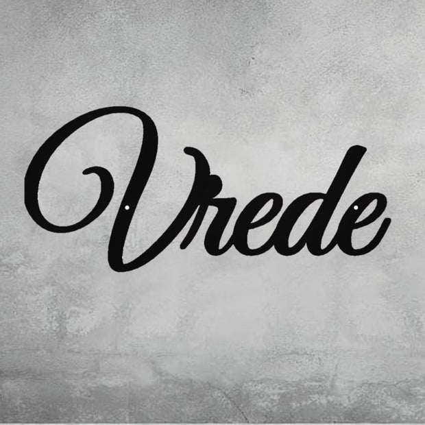 
A close-up of a decorative, black metal wall art piece that spells out the word "Vrede" in an elegant script font. The sign is mounted on a gray, distressed concrete wall. Art on Steel